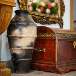 Vintage urn and wooden chest with decorative mirror in the background