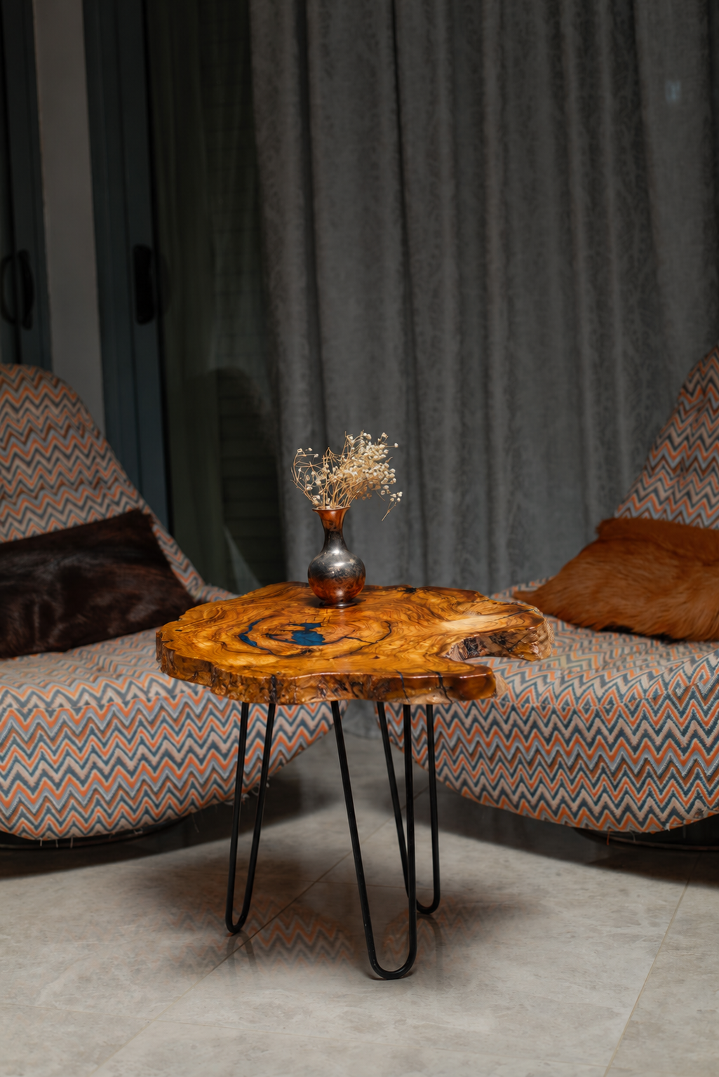 AI-styled view of Zitun Atelier table 002, an olive wood resin side table with teal resin knot, in a lounge setting with a vase on the tabletop.