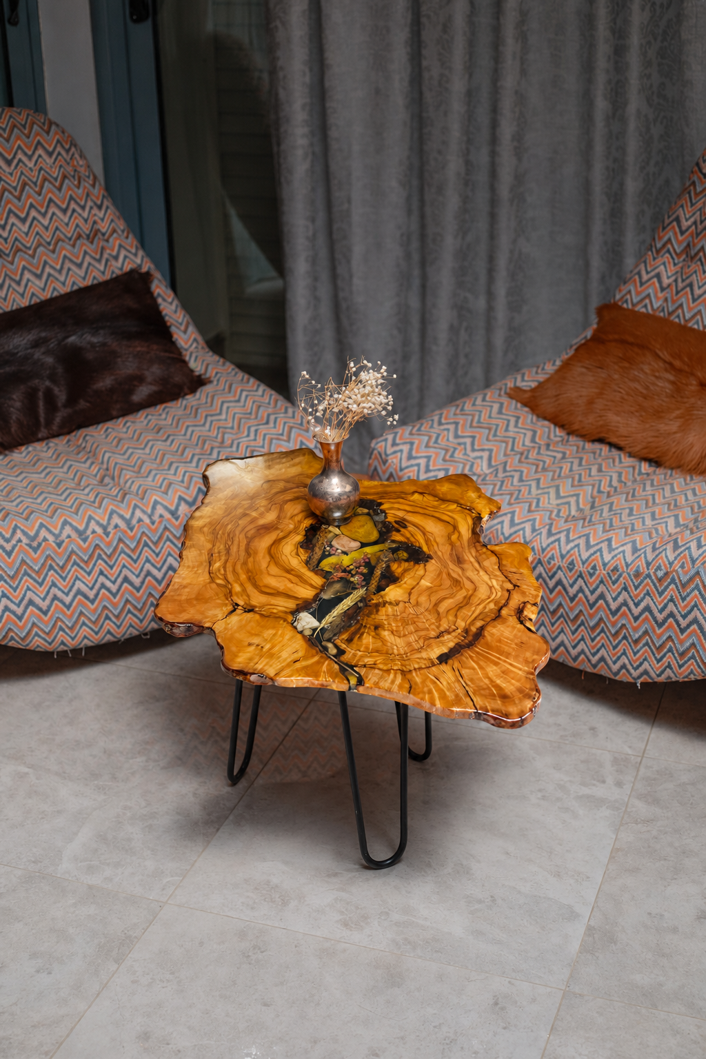 AI-styled view of Zitun Atelier table 003, an olive wood resin side table with black resin dried flowers, viewed from above between two upholstered armchairs.