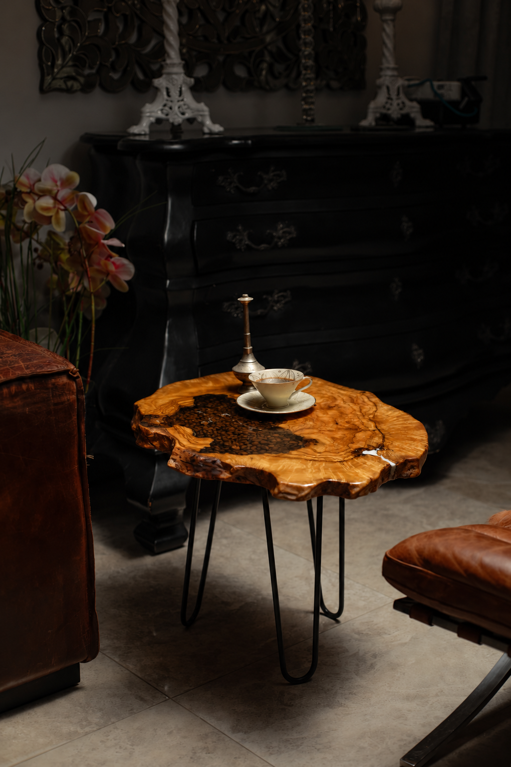 AI-styled view of Zitun Atelier table 004, an olive wood resin side table with coffee bean resin, in a dark interior beside leather seating.
