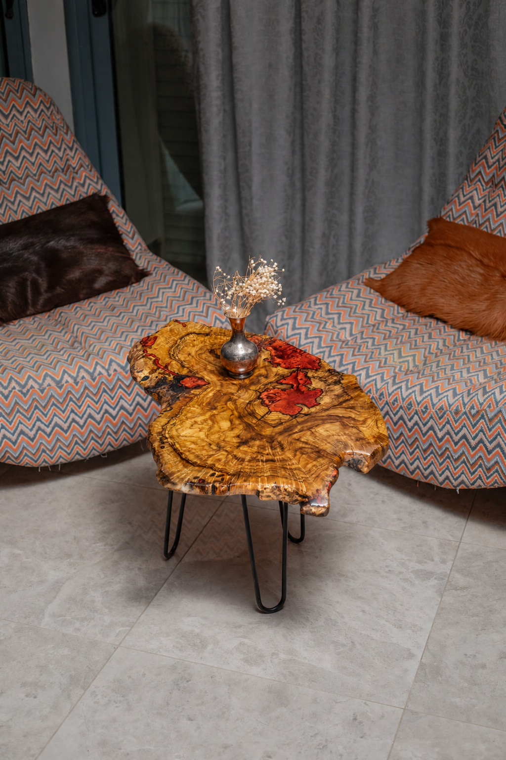 AI-styled view of Zitun Atelier table 005, an olive wood resin side table with red resin burl, viewed from above between two upholstered armchairs.