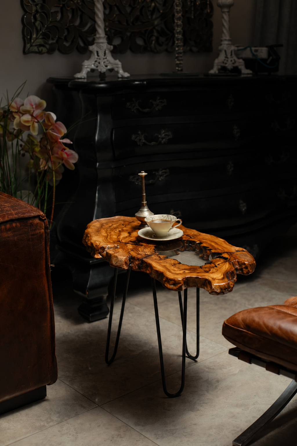 AI-styled view of Zitun Atelier table 006, an olive wood resin side table with white resin center, in a dark interior beside leather seating.