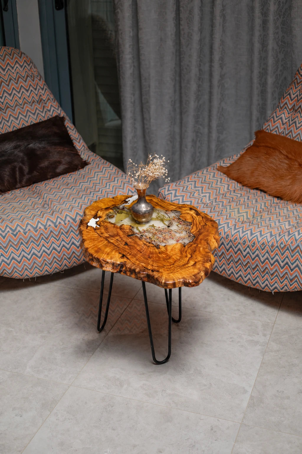 AI-styled view of Zitun Atelier table 007, an olive wood resin side table with white resin dried flowers, viewed from above between two upholstered armchairs.