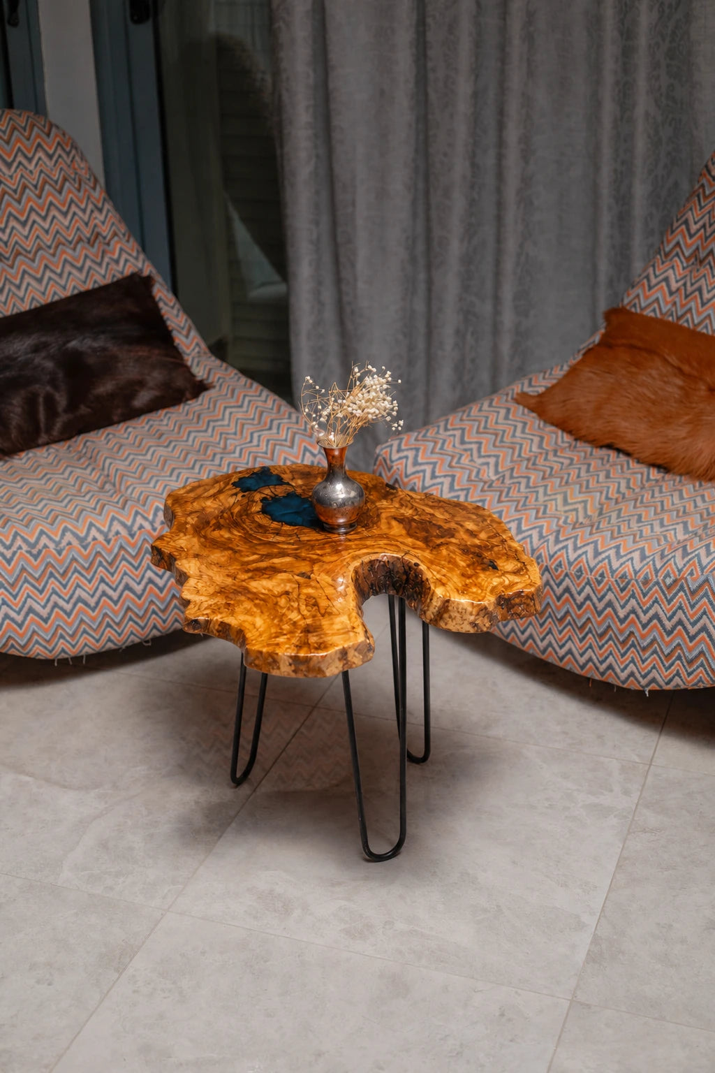 AI-styled view of Zitun Atelier table 008, an olive wood resin side table with dark teal resin burl, viewed from above between two upholstered armchairs.