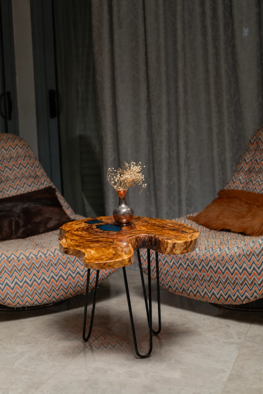 AI-styled view of Zitun Atelier table 008, an olive wood resin side table with dark teal resin burl, in a lounge setting with a vase on the tabletop.