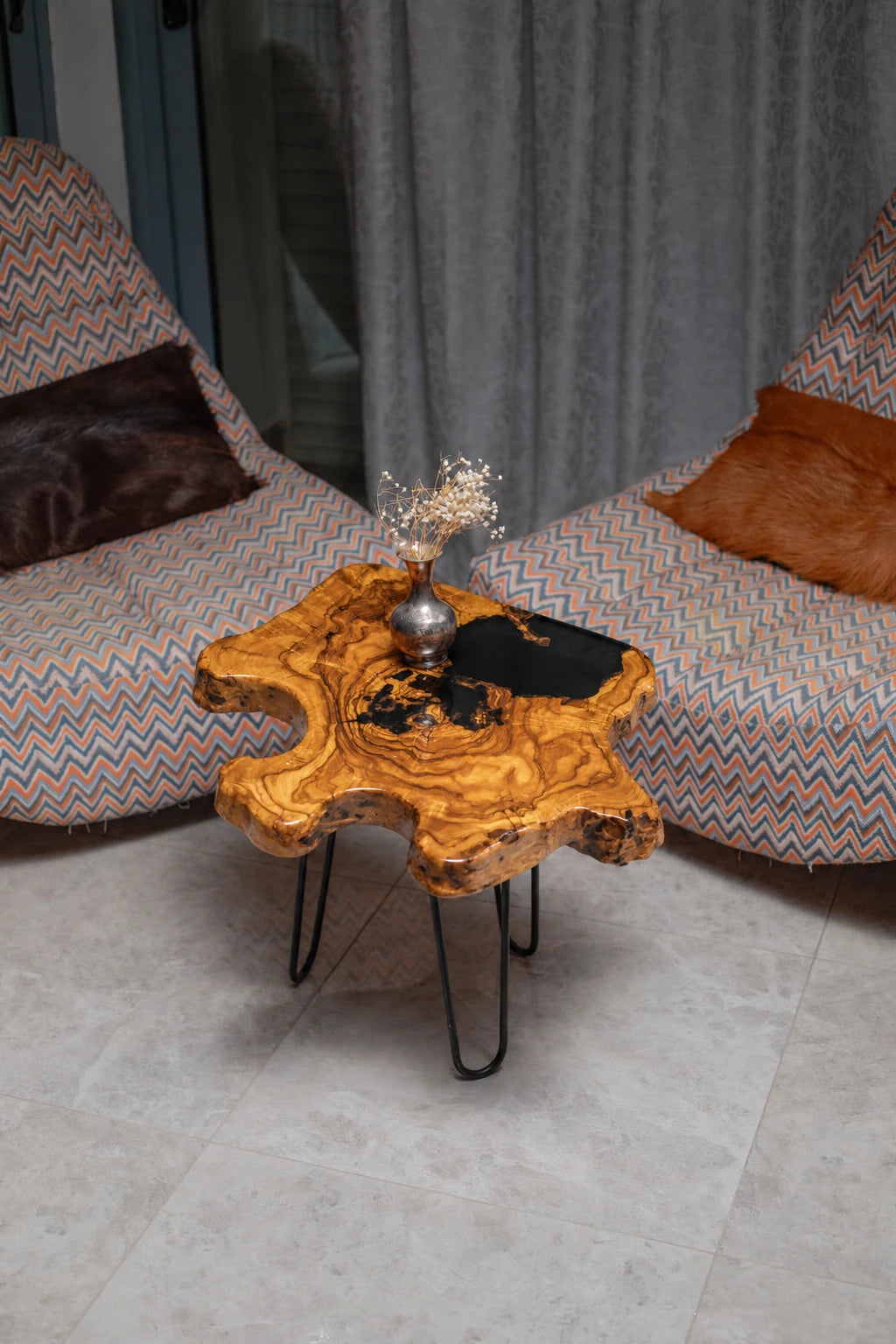 AI-styled view of Zitun Atelier table 009, an olive wood resin side table with black resin pour, viewed from above between two upholstered armchairs.
