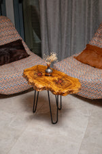 AI-styled view of Zitun Atelier table 011, an olive wood resin side table with red resin accents, viewed from above between two upholstered armchairs.