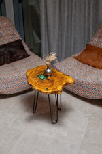 AI-styled view of Zitun Atelier table 012, an olive wood resin side table with emerald green star resin, viewed from above between two upholstered armchairs.