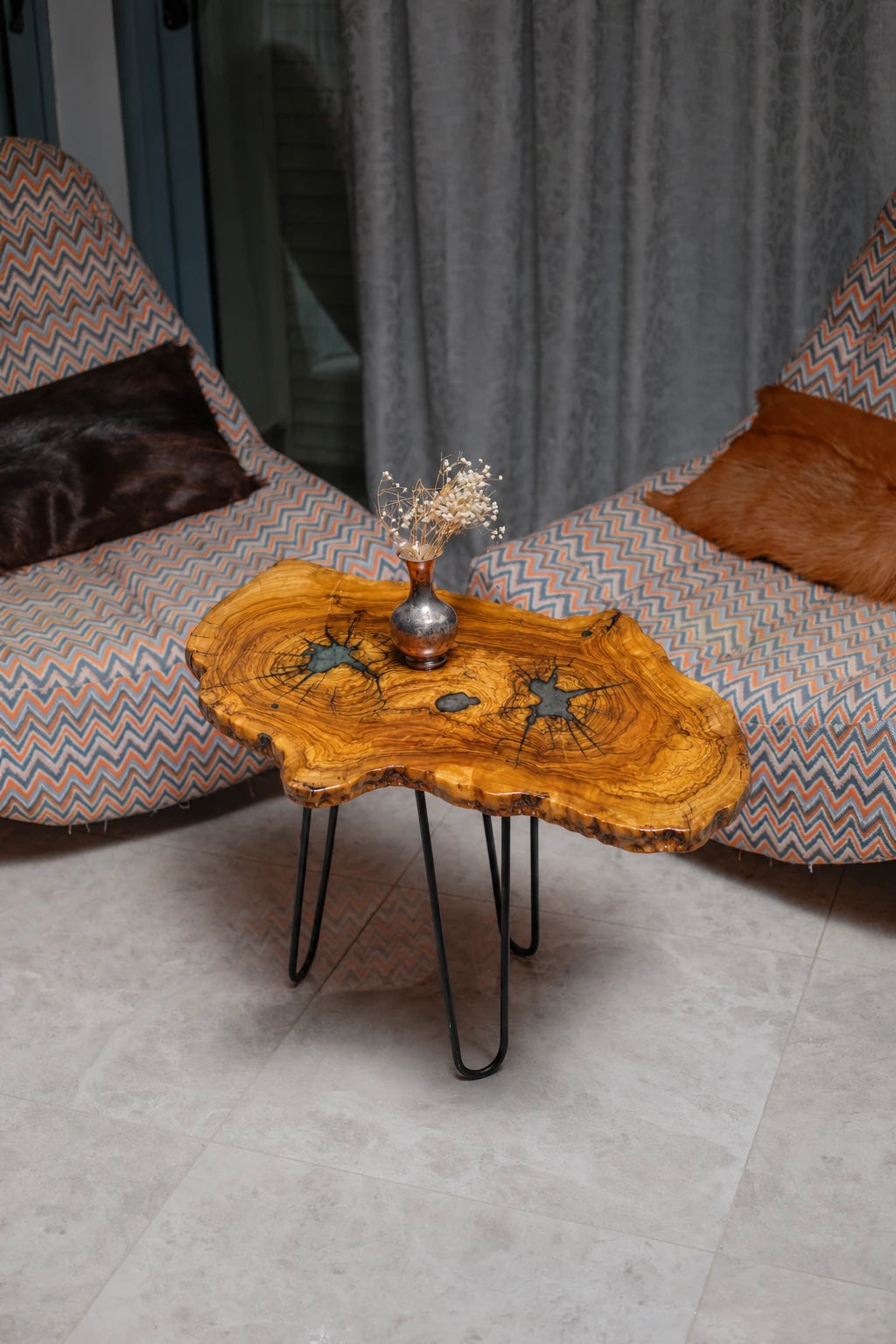 AI-styled view of Zitun Atelier table 013, an olive wood resin side table with teal starburst resin, viewed from above between two upholstered armchairs.