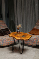 AI-styled view of Zitun Atelier table 013, an olive wood resin side table with teal starburst resin, in a lounge setting with a vase on the tabletop.