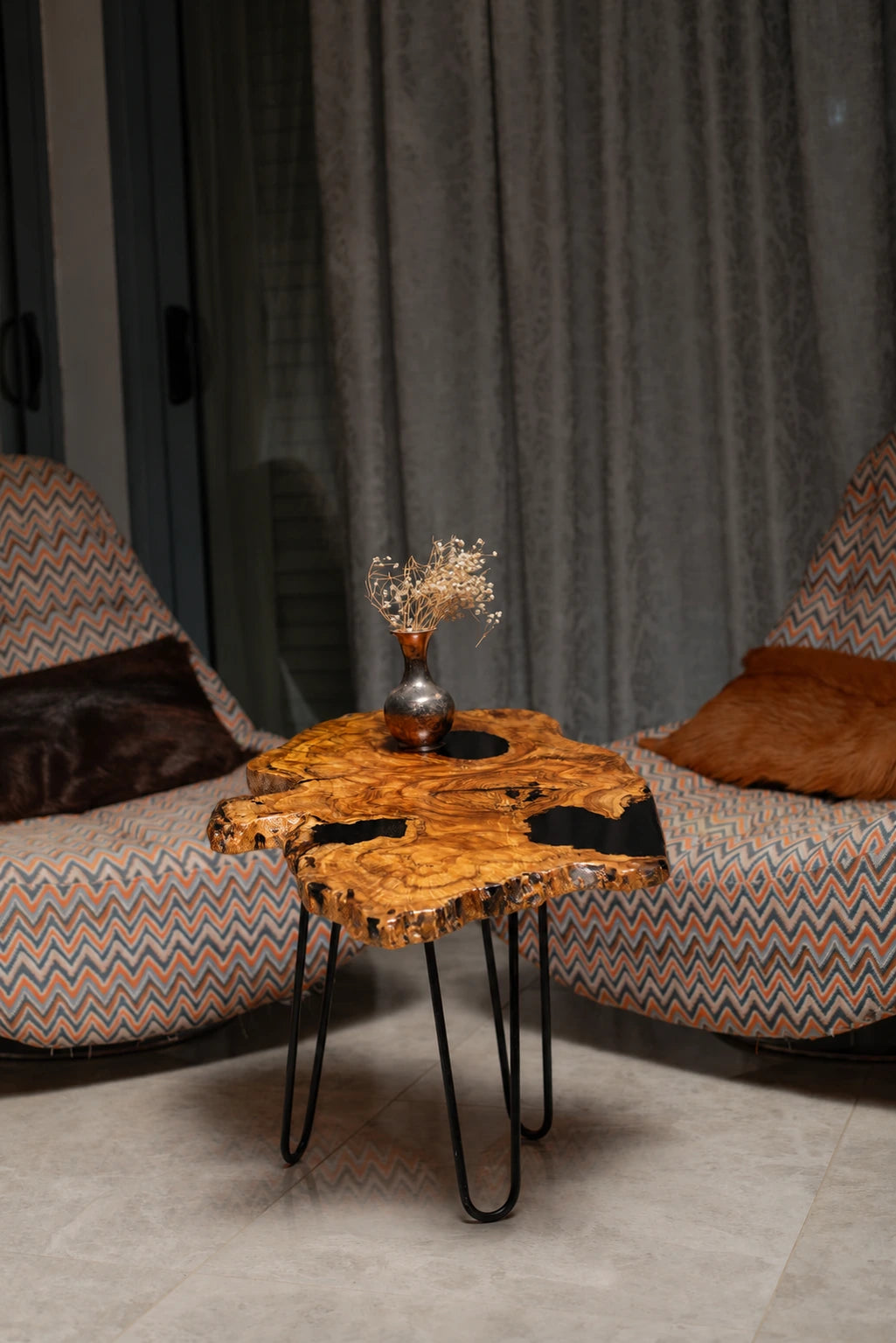 AI-styled view of Zitun Atelier table 014, an olive wood resin side table with black resin holes, in a lounge setting with a vase on the tabletop.