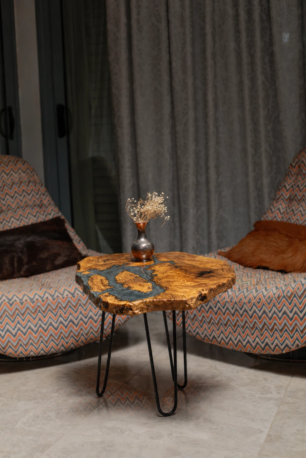AI-styled view of Zitun Atelier table 015, an olive wood resin side table with blue grey resin river, in a lounge setting with a vase on the tabletop.