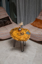 AI-styled view of Zitun Atelier table 016, an olive wood resin side table with grey resin inlay, viewed from above between two upholstered armchairs.