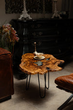 AI-styled view of Zitun Atelier table 019, an olive wood resin side table with white resin center, in a dark interior beside leather seating.