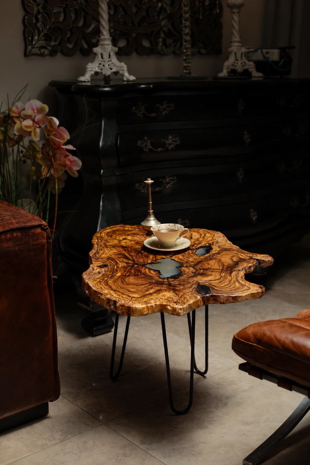 AI-styled view of Zitun Atelier table 019, an olive wood resin side table with white resin center, in a dark interior beside leather seating.