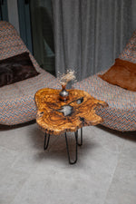 AI-styled view of Zitun Atelier table 019, an olive wood resin side table with white resin center, viewed from above between two upholstered armchairs.