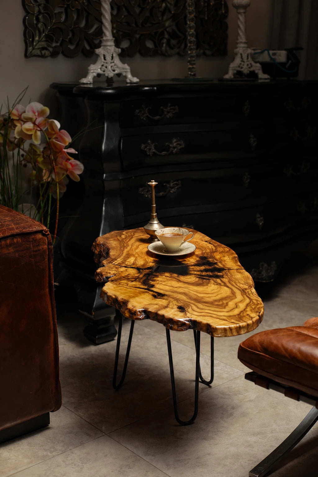 AI-styled view of Zitun Atelier table 021, an olive wood resin side table with black resin splash, in a dark interior beside leather seating.