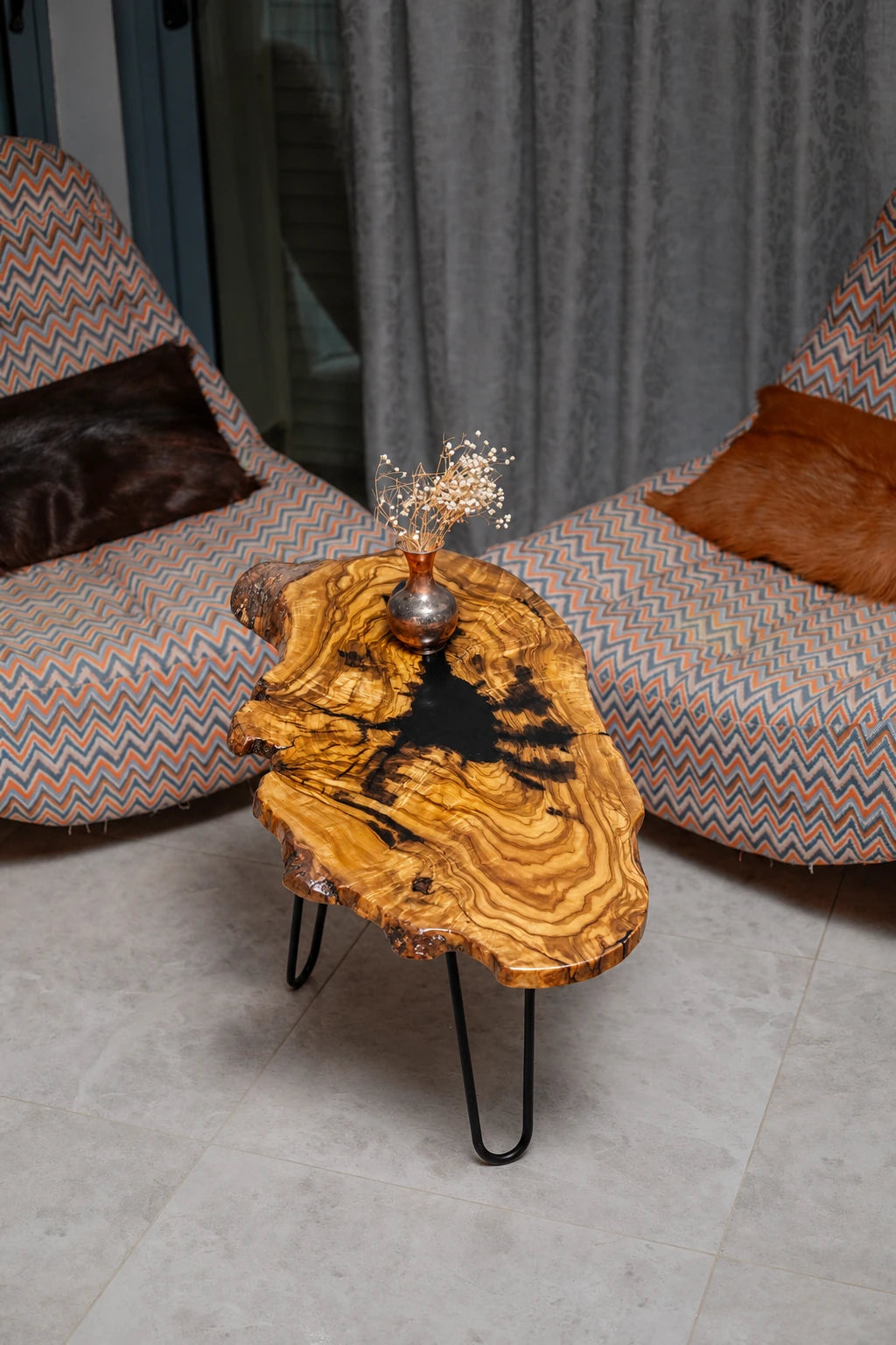AI-styled view of Zitun Atelier table 021, an olive wood resin side table with black resin splash, viewed from above between two upholstered armchairs.