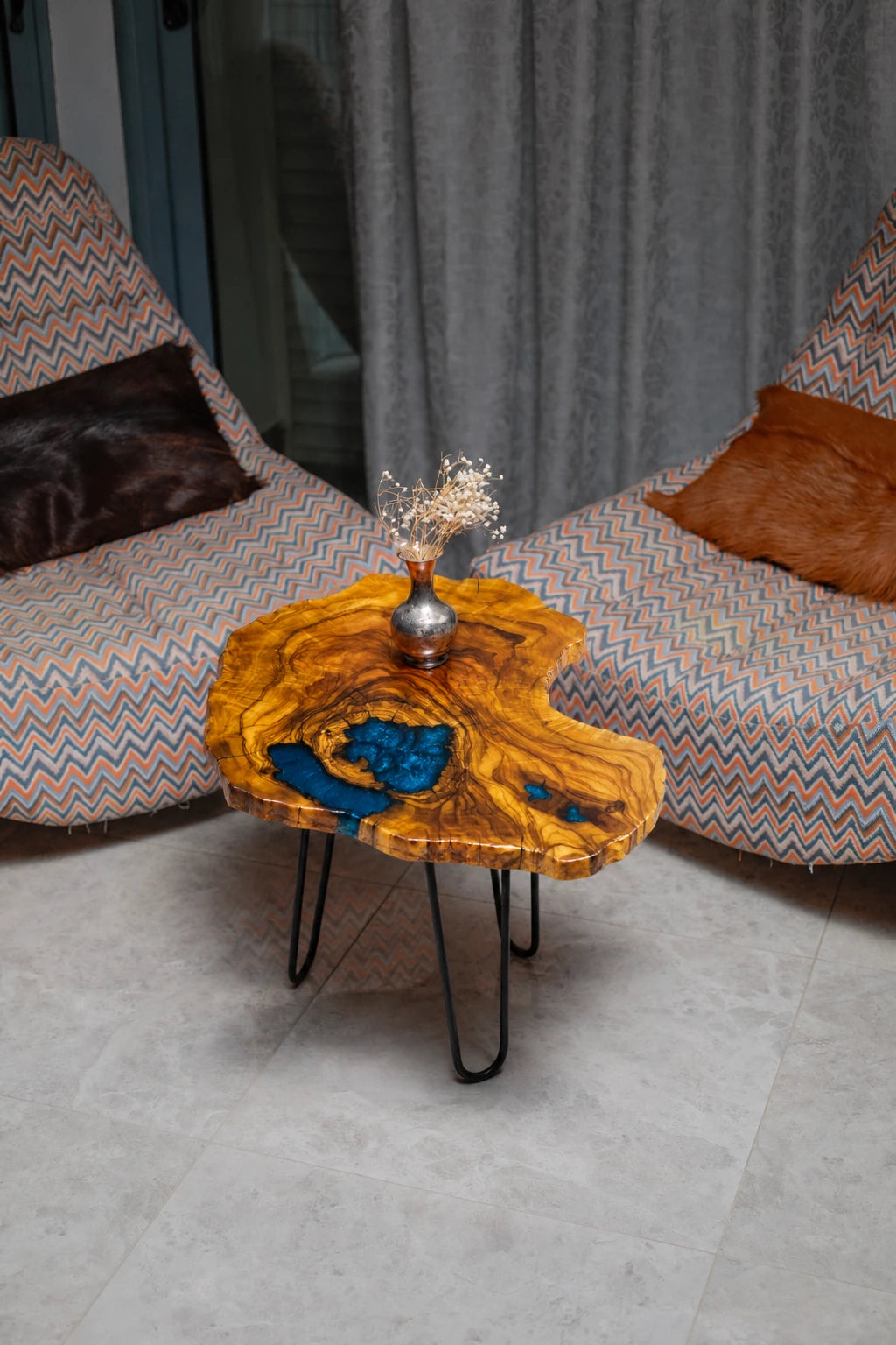 AI-styled view of Zitun Atelier table 022, an olive wood resin side table with blue resin inlay, viewed from above between two upholstered armchairs.