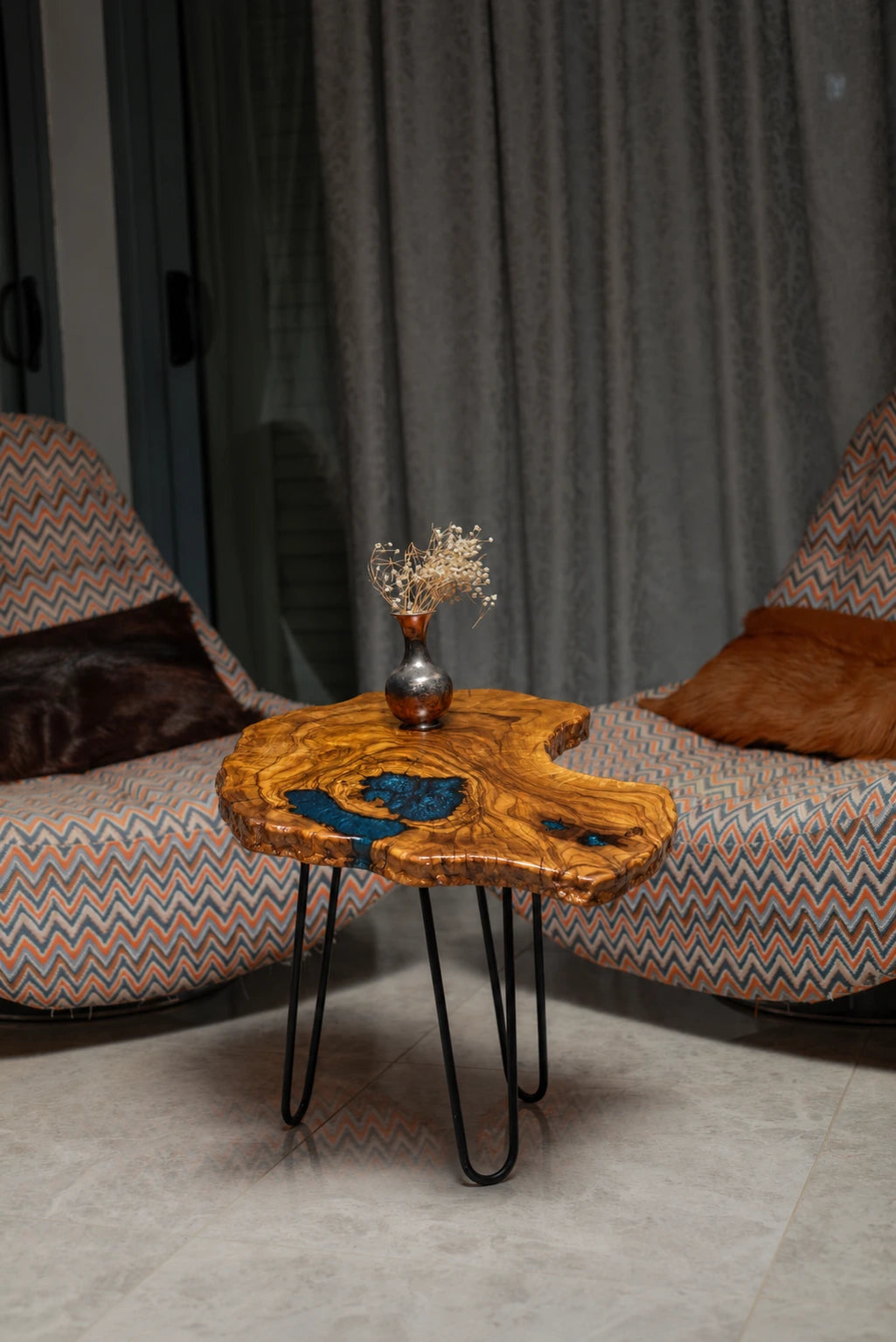 AI-styled view of Zitun Atelier table 022, an olive wood resin side table with blue resin inlay, in a lounge setting with a vase on the tabletop.