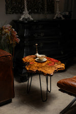 AI-styled view of Zitun Atelier table 023, an olive wood resin side table with copper red resin inlay, in a dark interior beside leather seating.