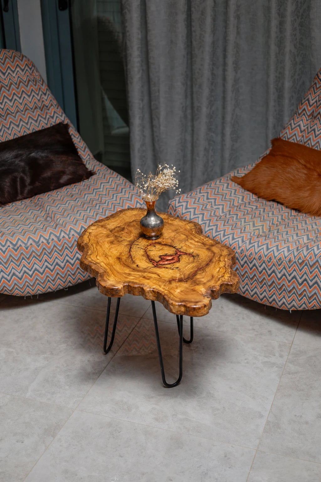 AI-styled view of Zitun Atelier table 024, an olive wood resin side table with copper red resin center, viewed from above between two upholstered armchairs.