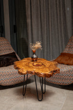 AI-styled view of Zitun Atelier table 024, an olive wood resin side table with copper red resin center, in a lounge setting with a vase on the tabletop.