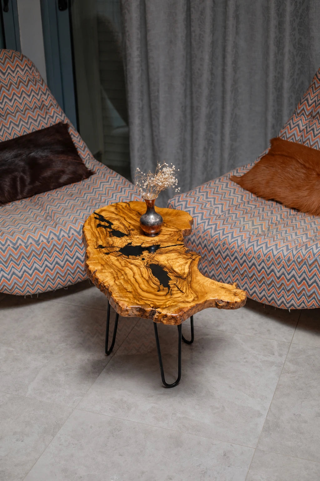AI-styled view of Zitun Atelier table 026, an olive wood resin side table with black resin veins, viewed from above between two upholstered armchairs.