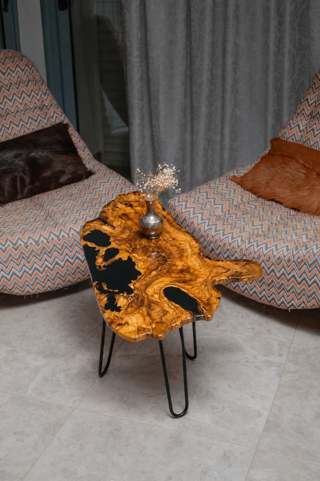 AI-styled view of Zitun Atelier table 027, an olive wood resin side table with black resin live edge, viewed from above between two upholstered armchairs.