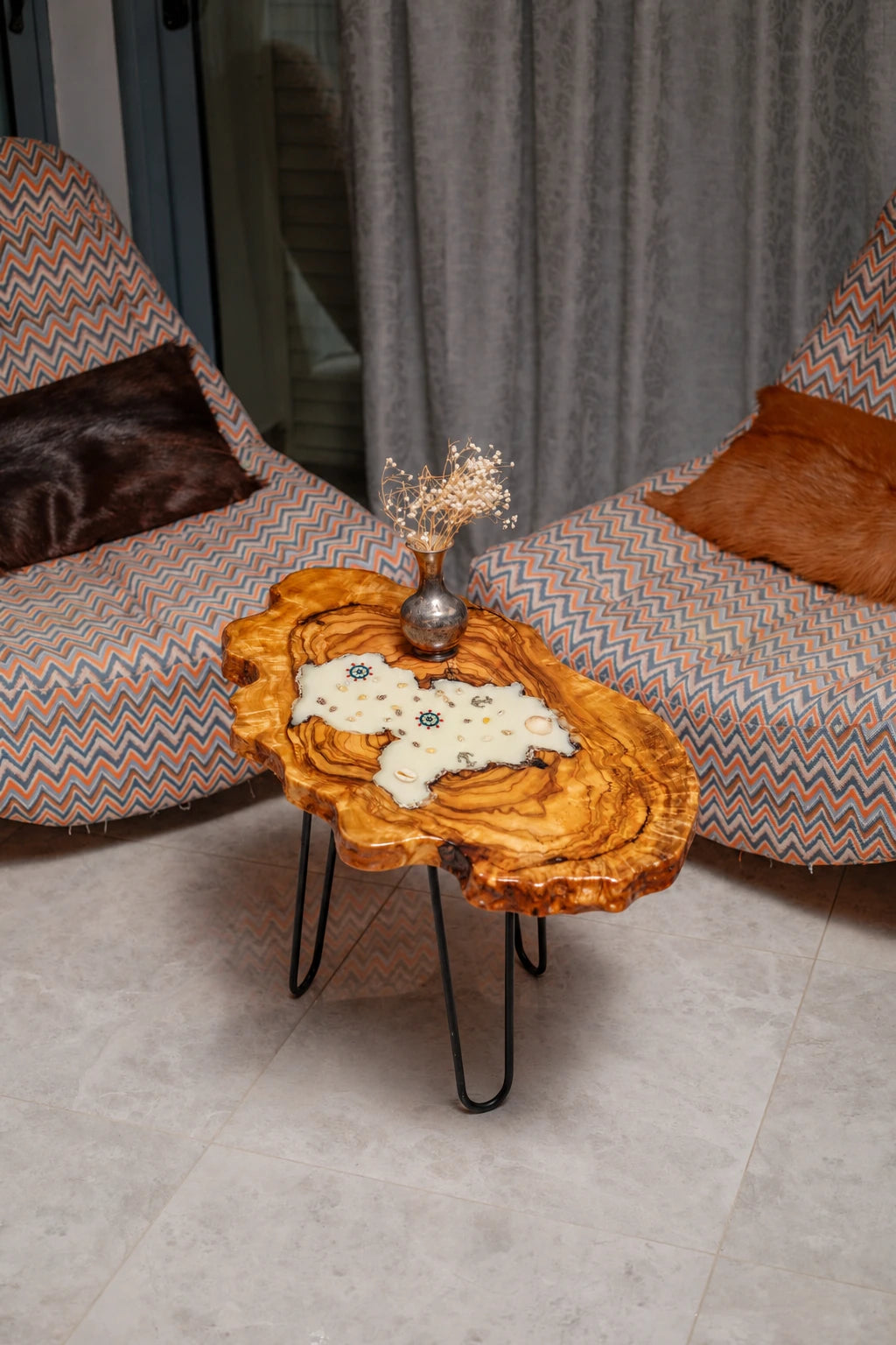 AI-styled view of Zitun Atelier table 028, an olive wood resin side table with white resin nautical charms, viewed from above between two upholstered armchairs.