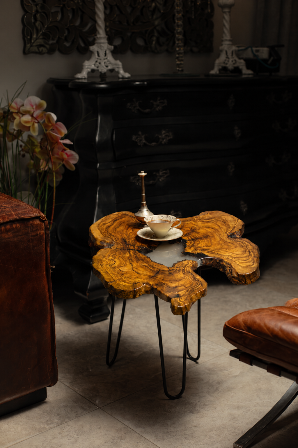 AI-styled view of Zitun Atelier table 029, an olive wood resin side table with white resin center, in a dark interior beside leather seating.