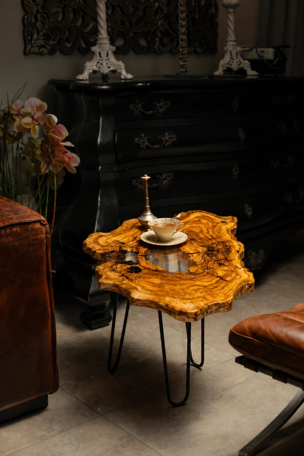 AI-styled view of Zitun Atelier table 030, an olive wood resin side table with white resin center, in a dark interior beside leather seating.