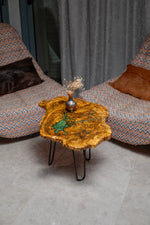 AI-styled view of Zitun Atelier table 031, an olive wood resin side table with emerald green resin veins, viewed from above between two upholstered armchairs.