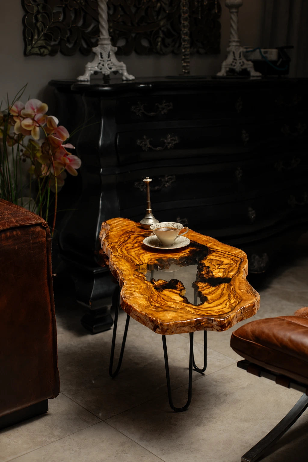AI-styled view of Zitun Atelier table 032, an olive wood resin side table with white black resin center, in a dark interior beside leather seating.