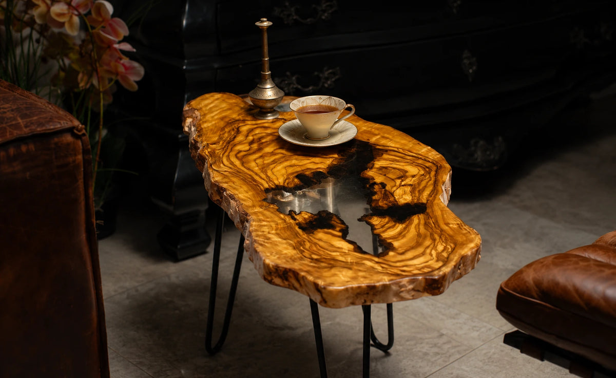 AI-styled view of Zitun Atelier table 032, an olive wood resin side table with white black resin center, in a dark interior beside leather seating.