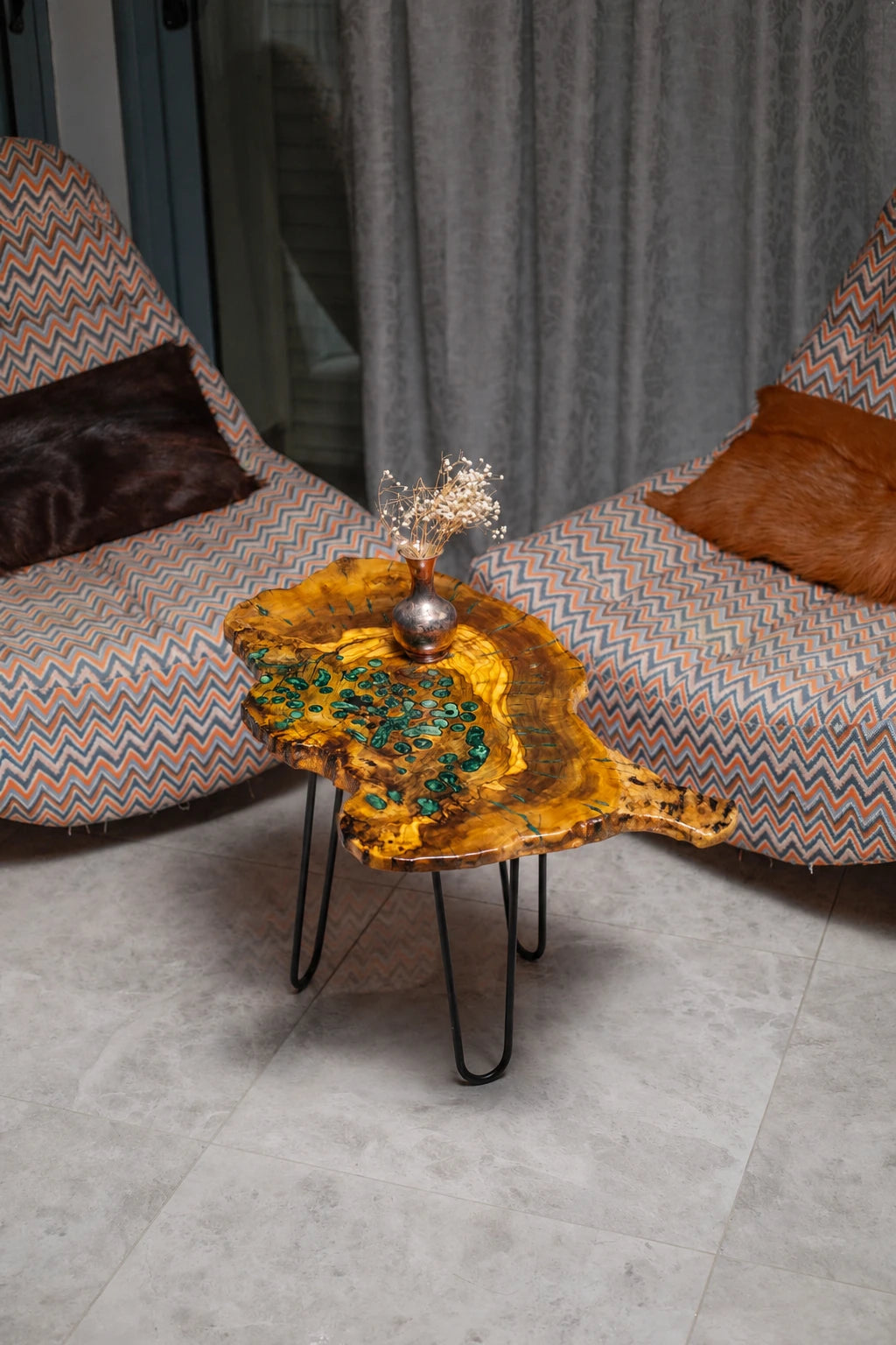 AI-styled view of Zitun Atelier table 033, an olive wood resin side table with green malachite resin, viewed from above between two upholstered armchairs.