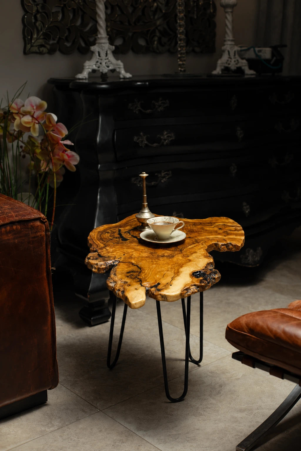 AI-styled view of Zitun Atelier table 034, an olive wood resin side table with black resin burl, in a dark interior beside leather seating.