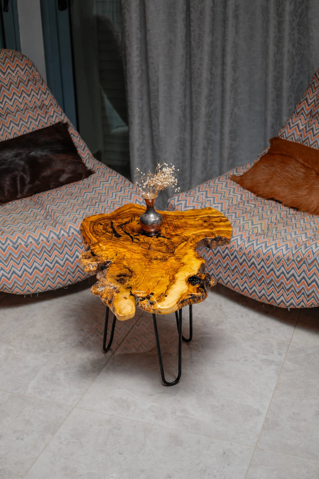 AI-styled view of Zitun Atelier table 034, an olive wood resin side table with black resin burl, viewed from above between two upholstered armchairs.