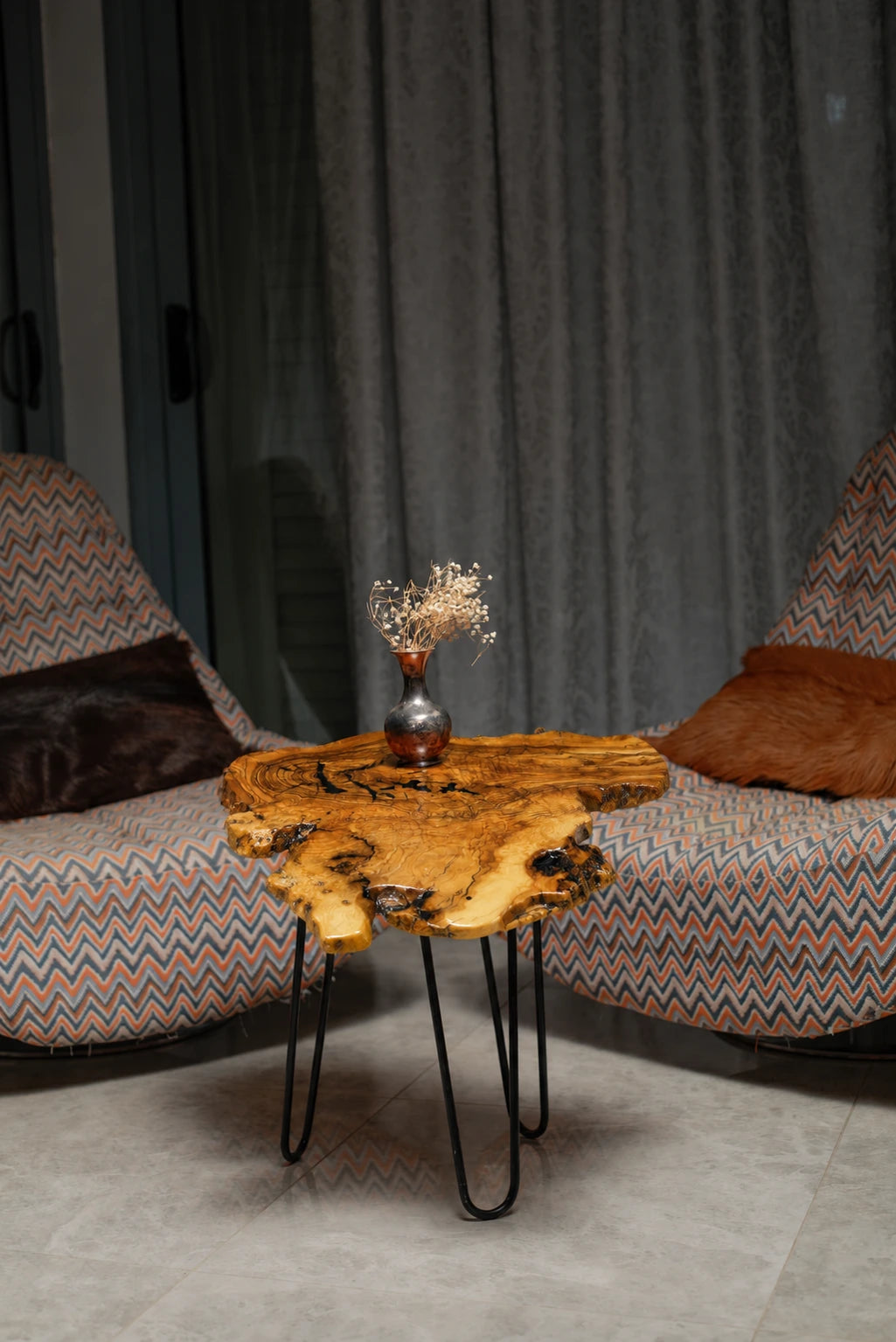 AI-styled view of Zitun Atelier table 034, an olive wood resin side table with black resin burl, in a lounge setting with a vase on the tabletop.
