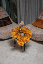 AI-styled view of Zitun Atelier table 035, an olive wood resin side table with white resin center, viewed from above between two upholstered armchairs.