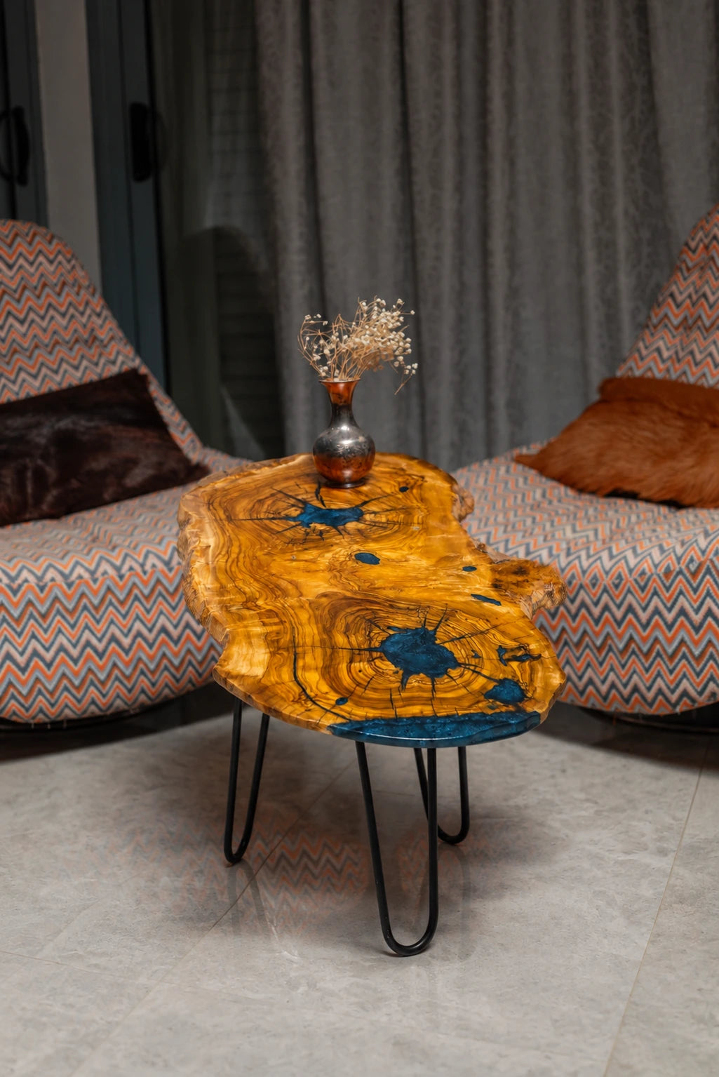 AI-styled view of Zitun Atelier table 036, an olive wood resin side table with blue starburst resin, in a lounge setting with a vase on the tabletop.