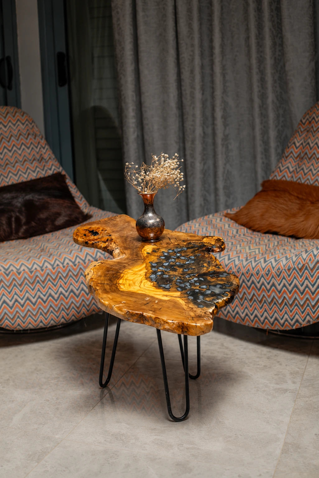 AI-styled view of Zitun Atelier table 037, an olive wood resin side table with blue pebble resin, in a lounge setting with a vase on the tabletop.