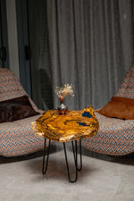 AI-styled view of Zitun Atelier table 038, an olive wood resin side table with blue resin accents, in a lounge setting with a vase on the tabletop.