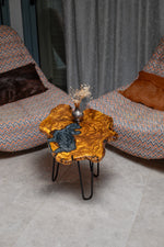 AI-styled view of Zitun Atelier table 039, an olive wood resin side table with grey swirl resin, viewed from above between two upholstered armchairs.