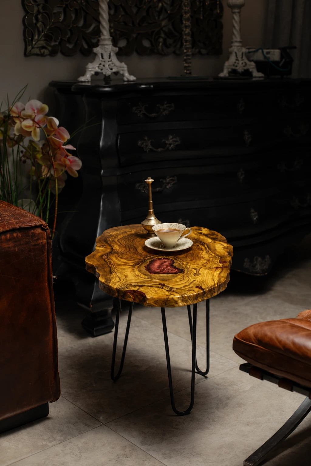 AI-styled view of Zitun Atelier table 040, an olive wood resin side table with red heart resin, in a dark interior beside leather seating.