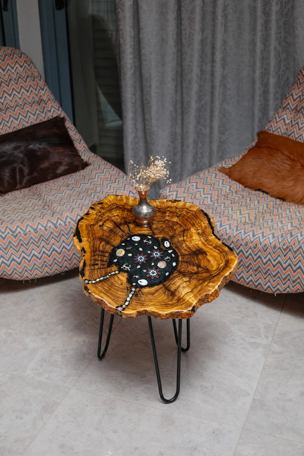 AI-styled view of Zitun Atelier table 044, an olive wood resin side table with black resin nautical charms, viewed from above between two upholstered armchairs.