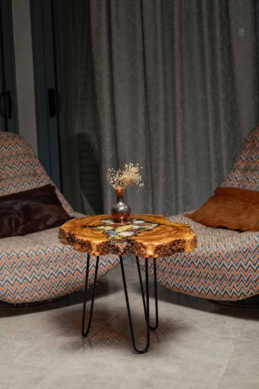 AI-styled view of Zitun Atelier table 047, an olive wood resin side table with sea shell pebble resin, in a lounge setting with a vase on the tabletop.