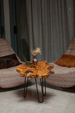 AI-styled view of Zitun Atelier table 048, an olive wood resin side table with burl live edge resin, in a lounge setting with a vase on the tabletop.