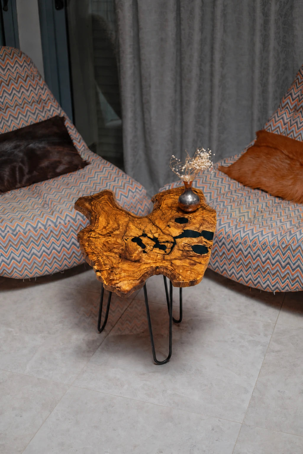 AI-styled view of Zitun Atelier table 049, an olive wood resin small coffee table with black resin spots, viewed from above between two upholstered armchairs.
