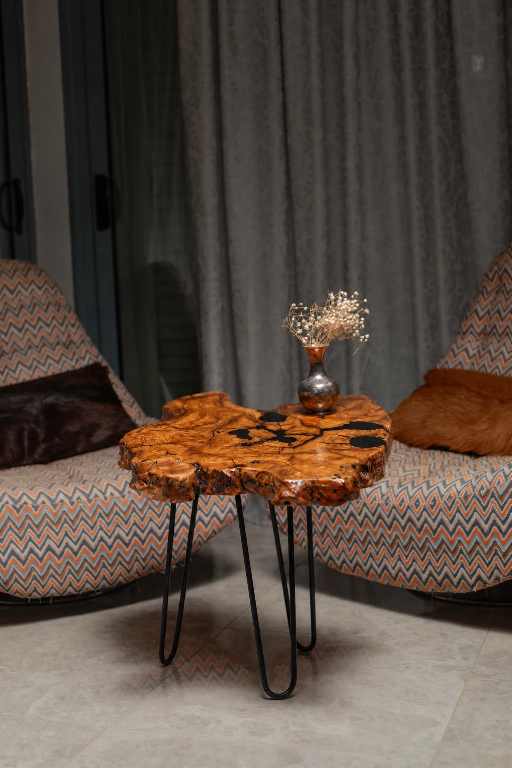 AI-styled view of Zitun Atelier table 049, an olive wood resin small coffee table with black resin spots, in a lounge setting with a vase on the tabletop.